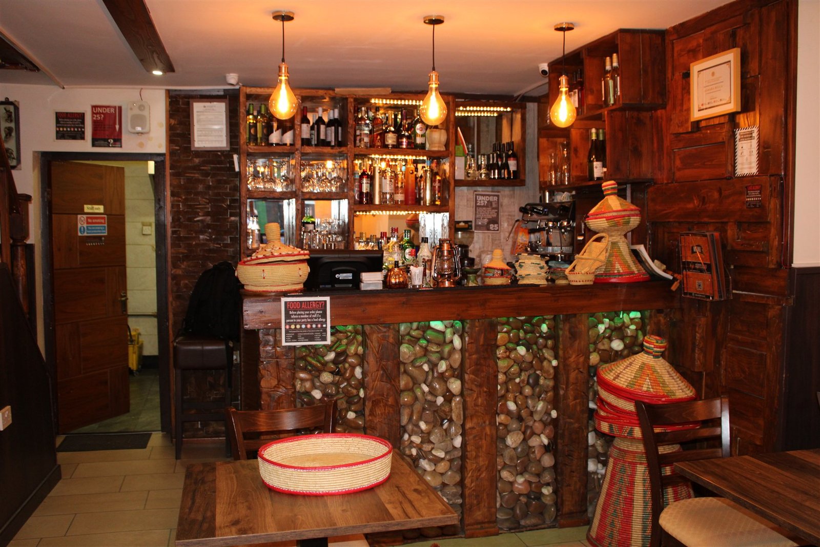 Inside Asmara Bella in Manchester — warm timber bar, Edison lighting and traditional Eritrean baskets